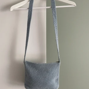 Ljusblå virkad väska från The Sak - Fin ljusblå virkad väska från The Sak. Liten crossbody väska. Använd, i gott skick.  Ett fack utvändigt samt ett fack invändigt med dragkedjor.