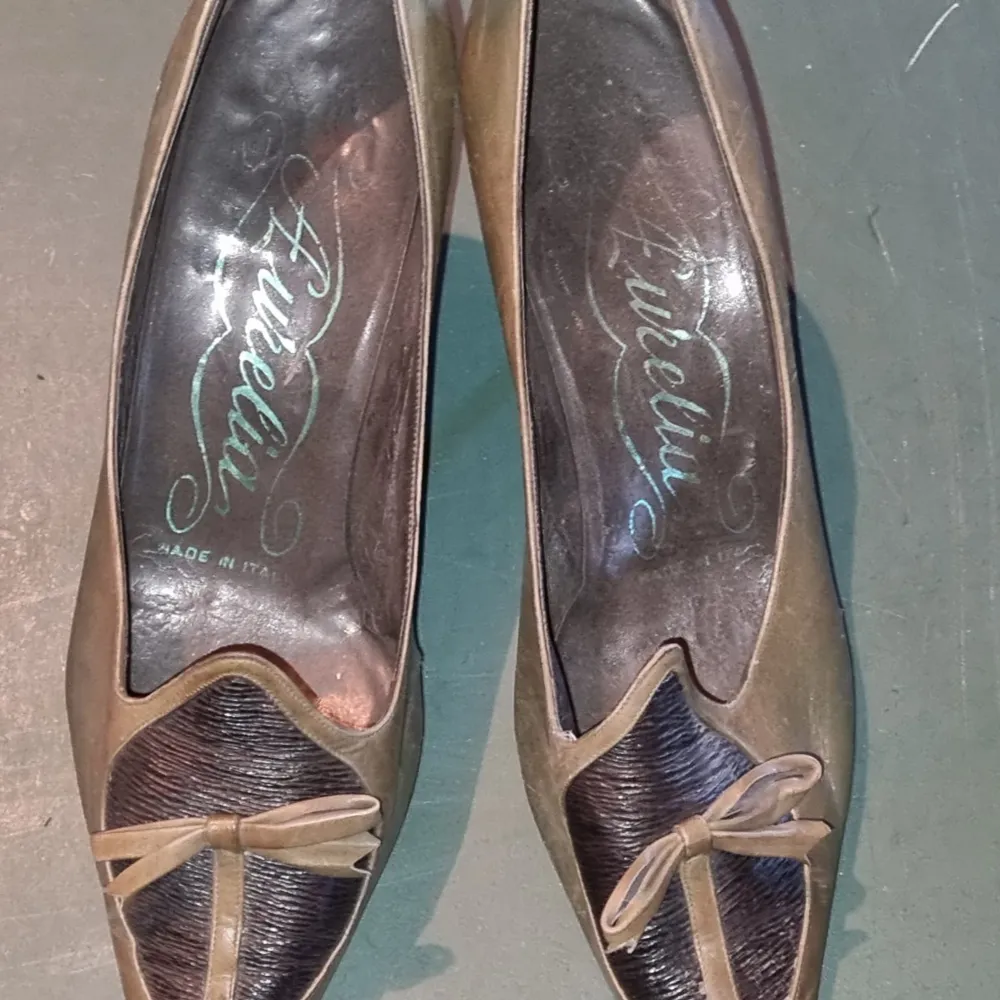 Ett par eleganta vintage bruna pumps med spetsig tå och en dekorativ rosett framtill. Skorna har en liten klack och är tillverkade i skinn.. Skor.