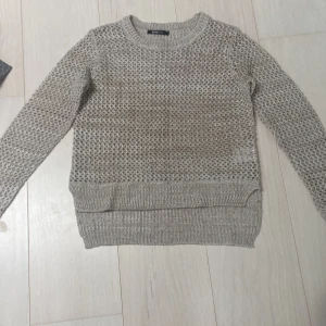  stickad tröja  - En beige fisk nät, stickad tröja från Gina Tricot i storlek XS. Tröjan har ett genombrutet mönster och är långärmad med ribbstickade muddar vid ärmslut och nederkant. bra skick och sann i storleken
