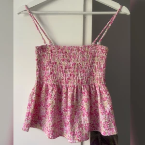 Bandeau/tubtopp/linne - Gina Tricot "Smock Singlet". Croppat linne, rosablommig i storlek XS. Avtagbara axelband. Helt ny med lappen kvar.