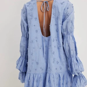 Blå NA-KD klänning - Säljer denna super gulliga blå blommiga klänningen från NA-KD som aldrig har kommit till användning 🩵Den är öppen i ryggen och har såå fina ärmar😍 Orginalpris 899kr, slutsåld, prislapp kvar 💕