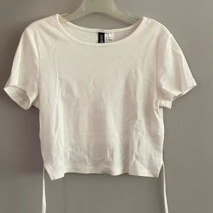 Vit croptop - Vit croppad T-shirt från H&M med knyte bak vid ryggen. Använd fåtal gånger så nästintill nyskick 💕