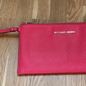 michael kors clutch  - Rosa Michael Kors Clutch. Väska är köra men har dessvärre inget kvitto kvar. Har en liten fläck men annars i superfint skick