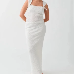 Gina Tricot vit set, storlek S - Snygg vit topp och kjol i ett set från Gina Tricot. Toppen har en söt detalj med band som knyts vid axlarna. Kjolen är lång och har en bekväm passform. Båda är i storlek S! Går jätte bra att köpa de ihop eller bara en utav de