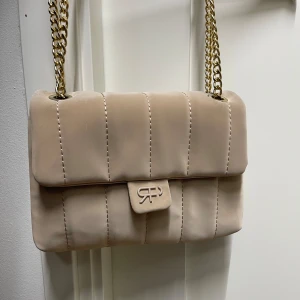 Beige handväska/axelväska - Väska i bra skick, liten grå fläck på sidan av tjedjan på tyget men ej så märkbart de bild 😊