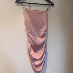 Rosa satin klänning - Säljer en superfin rosa klänning i satinmaterial med rynkdetaljer på baksidan.