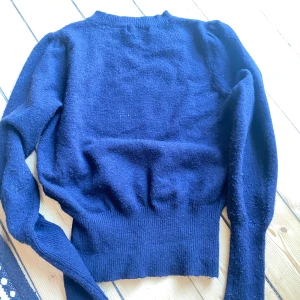 Mörkblå stickad tröja från Sandro Paris - Säljer en snygg och bekväm mörkblå stickad tröja från Sandro Paris. Tröjan har långa ärmar och en normal passform. Perfekt för höst och vinter! 🧶