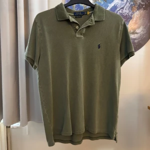Grön pikétröja från Polo Ralph Lauren - Säljer en snygg grön pikétröja från Polo Ralph Lauren i storlek L. Tröjan är i custom slim fit och har korta ärmar. Perfekt för både vardag och fest. Den är i bra skick och väldigt bekväm att ha på sig. Passa på att köpa denna klassiska tröja!