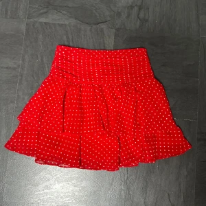 Röd kjol   - Säljer en superfin röd kjol från & Other Stories med vita prickar. Kjolen är kort med volangdetaljer. Perfekt för sommarens alla fester, en dag på stan eller temafester. Den är i storlek XS-34 och sitter bra i midjan. Skicket är i nyskick,  använd en gång. Säljer då den är för liten