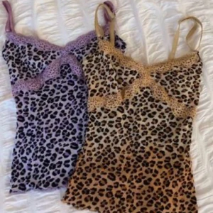 Leopardmönstrade linnen med spetsdetaljer - Säljer två snygga leopardmönstrade linnen med spetsdetaljer. Ett är i lila och svart medan det andra är i beige och svart. Båda har smala axelband och spets längs med halsringningen. Perfekta för en cool och trendig look!