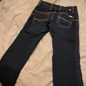 Mörkblå jeans  - INTE MIN BILD! Mörkblå jeans med färgade ränder på både sidorna och fickorna. Köpt på Vinted och säljer pga att de inte passade mig så bra!