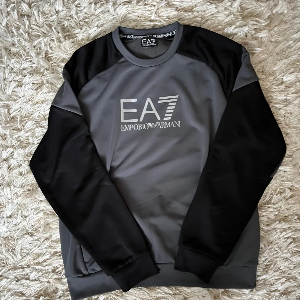 Långärmad EA7 tröja i färgen grå och svart. Nypris 1000kr. Väldigt bra skick och har aldrig blivit använd och har inga tecken på användning. Passar storleken M. Hoodies.