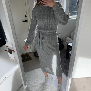 Stickad klänning  - En grå stickad klänning från bubbleroom med knyte i midjan och en slits bak. 