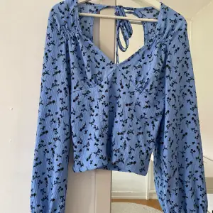 En blå topp/tröja som är använd endast en gång! Perfekt till sommaren då den är öppen i ryggen med ett knyte vid nacken🥰