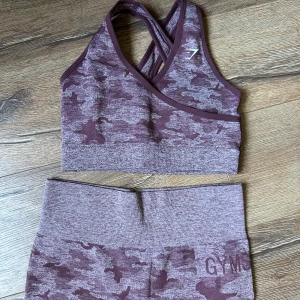 Gymshark camo set mörkröd strl M - Använd ett par gånger bara- i super bra skick. Hög midja och butt scrunch. Priset avser både topp och leggings.  
