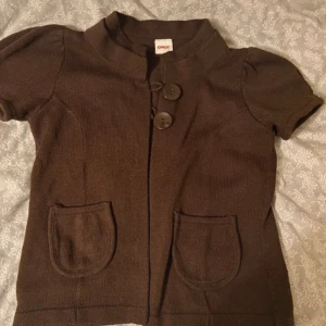 Bolero/kofta - En kortärmad kofta med knäppe i halsen   Står m men sitter som s 