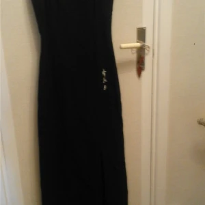 POURQOI PAS Svart klänning med slits Strl 38 / M  - POURQOI PAS  Svart klänning med slits och kinetisk teaken i vitt Strl 36 väldigt töjbar passar en 38 / M  Mått  längd 104cm från armhålan å ner över bröst från söm till söm 36cm slits längd 51cm skick fint