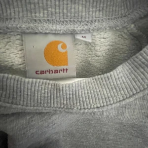 Grå carhartt sweatshirt  - Säljer denna gråa Carhartt i storlek M. Då den är lite oversized passar den även lite större. Den har inga fläckar eller hål så är i relativt bra skick! Hör av er vid funderingar🤍