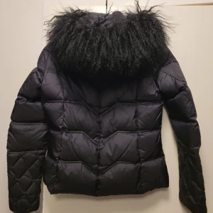 Saki dunjacka med mongolian lambfur - Jätte fin dunjacka av Saki i storlek 38 men passar till 36. Lite tajt på mig.  Avtagbar huva och även päls.  100% dun. Finns mer bilder vid intresse. 