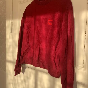 Ceriserosa collegetröja  - Mörk cericerosa collegetröja med röd broderad text. Köpt på NA-KD och är i storlek S. Har inga fläckar eller hål och är i bra skick.