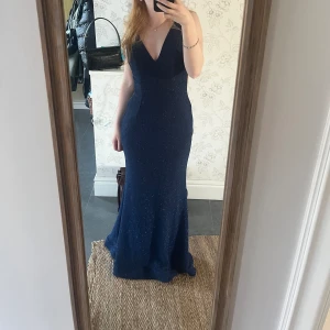 Balklänning - Mörkblå glittrig balklänning med djup rygg . Super fin!!!! Säljer då jag hittat en annan balklänning. Den är köpt på plick tidigare, för lång för mig (166) men med klackar passar den perfekt. Storlek 34. Från Christian koehlert.