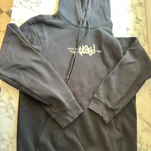 Svart HM tröja med tryck - En svart HM tröja med tryck i storlek XS. Tröjan har använts flertalet gånger men funkar ändå att användas. Den svarta färgen har aningen försvunnit men syns ändå vara klart svart. Passformen är tajt på kroppen och det finns även tryck på ryggen.