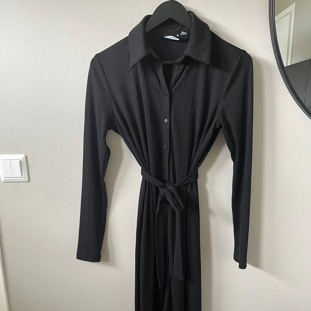 Fin svart klänning med knytband från VILA. Sparsamt använd. Finns inga hylsor på klänningen, så den går även att använda utan band. Klänningar.
