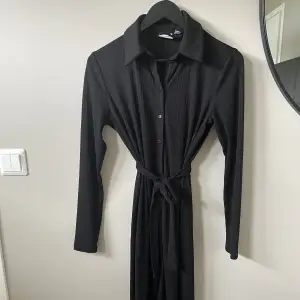 Fin svart klänning med knytband från VILA. Sparsamt använd. Finns inga hylsor på klänningen, så den går även att använda utan band
