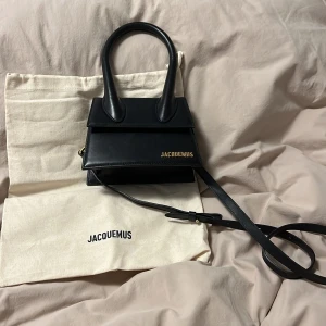 Jacquemus handväska svart - Säljer min i stort sätt felfria jacquemus väska! Måtten är 18cm lång där nere och 15cm där uppe. Den är 11cm djup & 7cm bred! Väskan är använd men har varit väldigt rädd om den vilket syns! Säljer därför jag har tröttnat på den lite😊Pm vid frågor!💞
