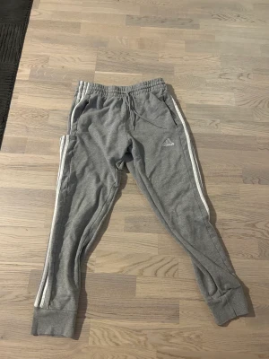 Adidas grå mjukisbyxor - Adidas gråa 3 stripe sweatpants storlek m knappt använda, för små för mig.