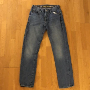 Lee Extreme Motion MVP Jeans - Ett par blå jeans från Lee's Performance Series, modell Extreme Motion MVP. De har en klassisk femficksdesign och en läderpatch med Lee-logotypen på baksidan. Byxorna har passformen straight Fit Tapered Leg.