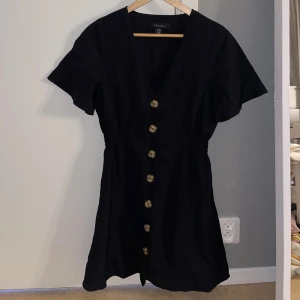 Svart klänning med knappar - Jättefin svart klänning med knappar som är lite tajtare i midjan så det skapas en fin siluett. Klänningen slutar ungefär ovanför knäna på mig. Använd ett fåtal gånger. Storlek 38, normal i storleken. köparen står för frakt ☺️