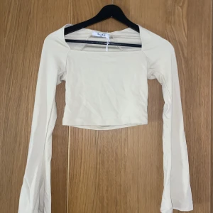 Beige tröja - Beige tröja från NA-KD. Lite kortare modell med trumpet armar. Jättefin men helt oanvänd då den inte passade mig. Den är i strl xxs men skulle säga den passar xxs. Köparen står för frakten.