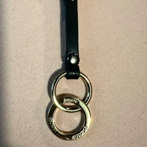 Efva Attling nyckelring Twosome - Nyckelring med ett guldfärgat smycke från Efva Attlings kollektion Twosome.  Konstläder, polyester, mässing.