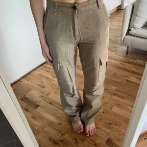 Cargobyxor - Skitsnygga beiga cargobyxor i rak modell. Perfekt långa för mig som är 165 cm, men skulle även passa någon längre. Från Stradivarius, strl 38. Använda endast en gång. Säljer då de är för stora på mig.