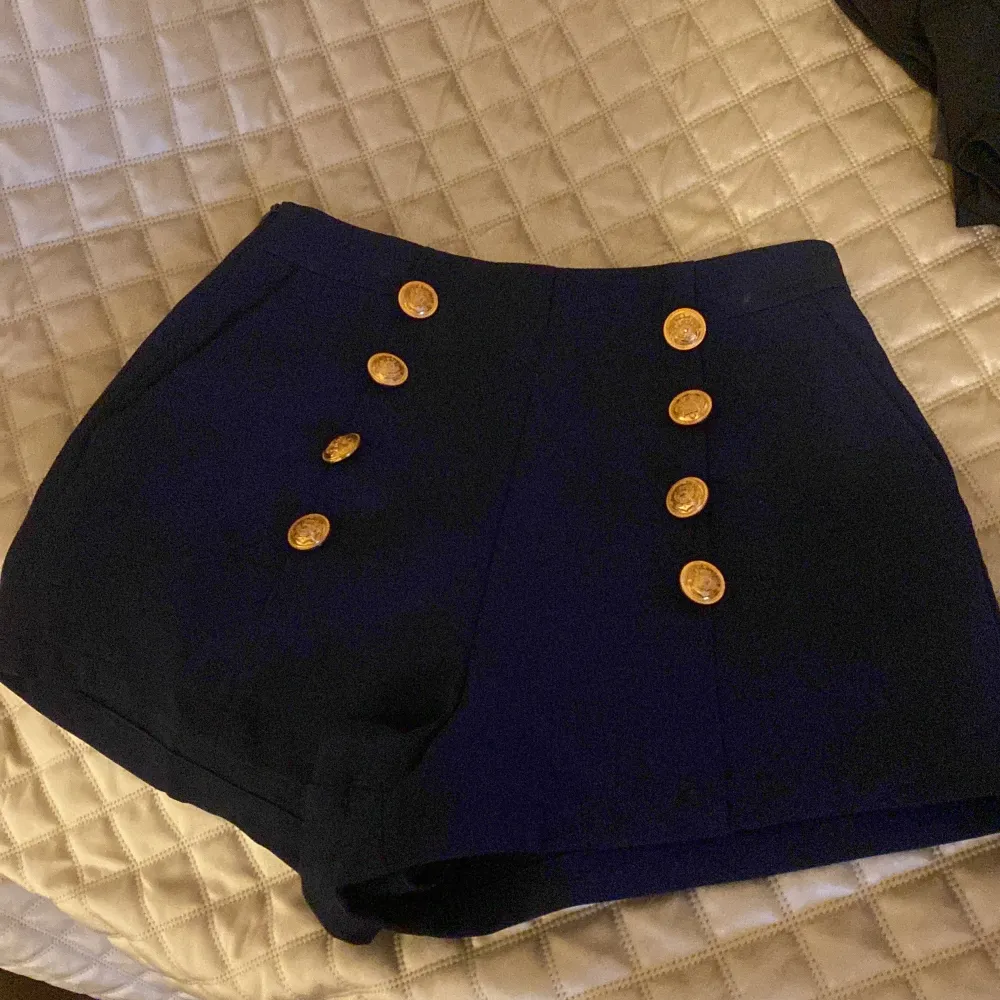 Oanvända marinblå shorts med exklusiva guldknappar som detaljer, fickor finns även i sidorna. Storlek xs (34) dam  Lappen från märket är borta men vad jag minns är de inköpta från Zara. Shorts.