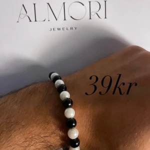 Armband från Almori - Ett stilrent armband från Almori med svarta och vita pärlor. Armbandet är elastiskt och passar de flesta handleder.