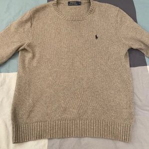 Grå stickad tröja från Polo Ralph Lauren - En grå stickad tröja från Polo Ralph Lauren med rund halsringning och ribbstickade muddar vid ärmslut och nederkant. 9/10 skick inga defekter 
