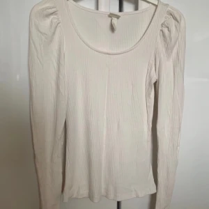 Vit långärmad topp tröja ribbad puffärm detaljer Stockholmstil Stockholmsstil coquette - Vit ribbad tröja med liten puffärm. Inga hål eller fläckar! Lite nopprig på vissa ställen.