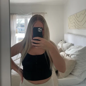 Svart topp - Fin svart topp med tunna band och knappar över bröstet  Använd ca 3ggr