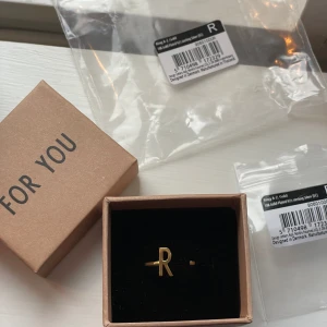 Guld ring - Bokstav R - Helt oanvänd ring formad som bokstaven R från märket Design Letters.  ONESIZE - i och med att den är öppen kan man justera själv! 18K pläterad Nypris: 569kr