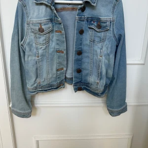 Jeansjacka Tommy Hilfiger  - Jeansjacka från Tommy Hilfiger i nyskick i strl 128. Knappt använd, tvättad 1 gång inför försäljning. 