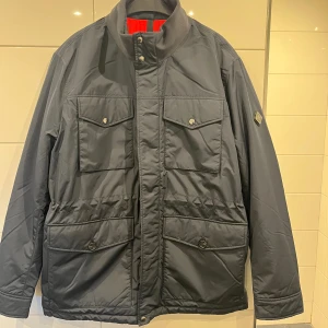 J Lindeberg Field jacka  - Helt ny j Lindeberg Field jacka med tags kvar i storlek L. Såklart helt oanvänd och i absolut topp skick. Sjukt fräsch perfekt till våren. Utfällningsbar luva. Nypris 4000kr. Hör av dig vid funderingar. Pris kan diskuteras