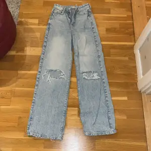 Ljusblåa högmidjade jeans i en rak modell med hål i. 