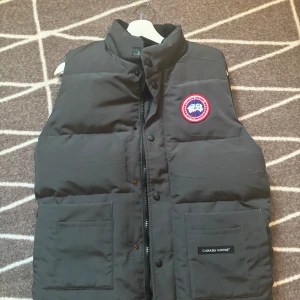 Canada goose väst grå - Jag har haft västen ganska länge så 1 knap upp i västen saknas för mer bilder privat  