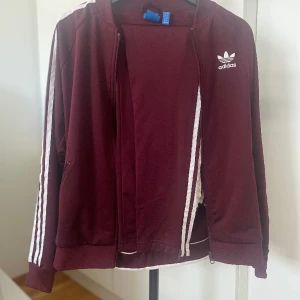Adidas set tröja byxor slits  - Snyggt set från Adidas. Storlek S. Använd fåtal tillfällen. Fin vinröd/plommonfärgad.