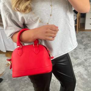 Röd väska i nyskick! Har både ett kort och långt band. Aldrig använd. Perfekt accessoar för att göra en tråkig outfit snyggare!