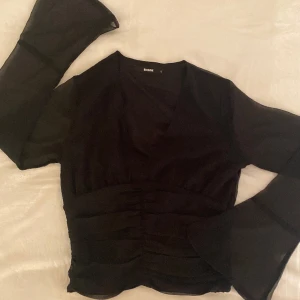 Svart blus - Långärmad blus som har ett genomskinligt tyg (ish) på armarna som även är utsvängda. Formar kroppen fint.