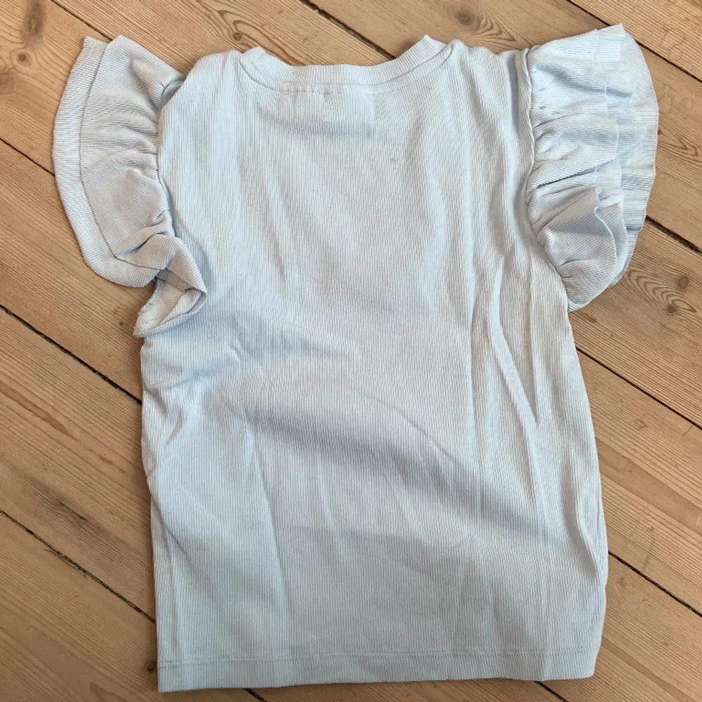 Jag säljer min ljusblå volang t-shirt från Gina tricot i storlek 146-152. Inte alls använd. . Toppar.