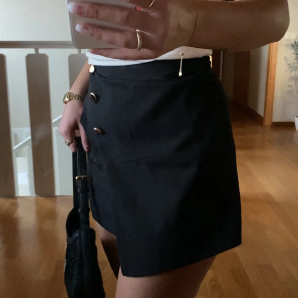 Säljer denna söta svarta kjol som har shorts under!🙌🏼🐚 Gulliga guldknappar på Använd fåtal gånger Fint skick!!. Kjolar.
